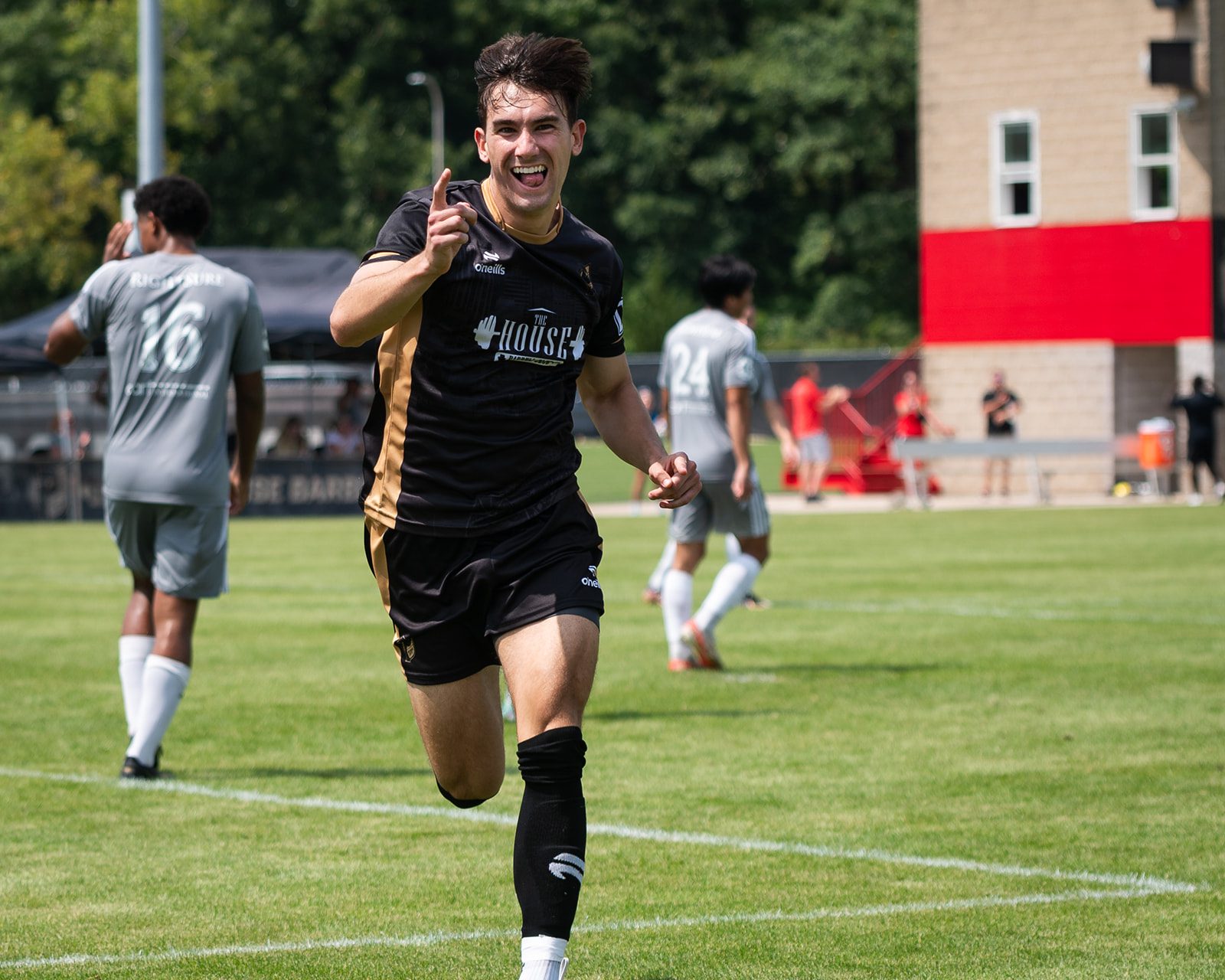 A happy soccer player running on the field towards the camera